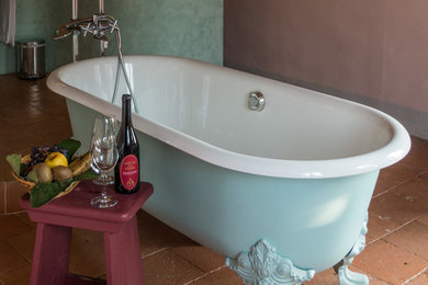 Ispirazione per una stanza da bagno country di medie dimensioni con ante viola, vasca con piedi a zampa di leone, pavimento in terracotta, pavimento rosso e pareti rosa