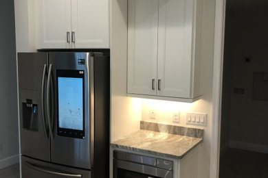 Mid-sized elegant l-shaped light wood floor and beige floor eat-in kitchen photo in Other with shaker cabinets, white cabinets, stainless steel appliances, an island and gray countertops