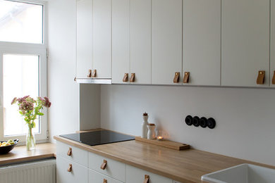 Danish eat-in kitchen photo in Other with flat-panel cabinets, white cabinets and wood countertops