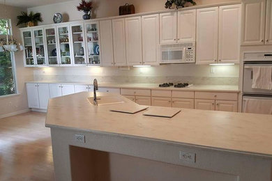Example of a large minimalist kitchen design in Sacramento with an integrated sink, solid surface countertops and an island