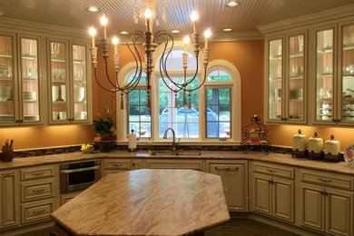 This is an example of a traditional u-shaped separate kitchen in New Orleans with an undermount sink, raised-panel cabinets, white cabinets, stainless steel appliances and with island.