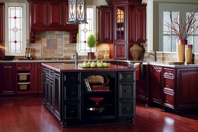 Enclosed kitchen - large transitional u-shaped medium tone wood floor and brown floor enclosed kitchen idea in Chicago with an undermount sink, raised-panel cabinets, dark wood cabinets, beige backsplash, stone tile backsplash, stainless steel appliances and an island