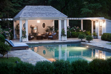 This is an example of a traditional rectangular pool in New York with natural stone pavers and a pool house.