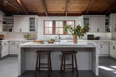 Example of a transitional u-shaped gray floor and wood ceiling kitchen design in San Francisco with a farmhouse sink, shaker cabinets, white cabinets, white backsplash, stainless steel appliances, an island and white countertops