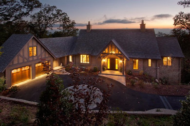 Large elegant beige stone house exterior photo in Other with a shingle roof and a gray roof