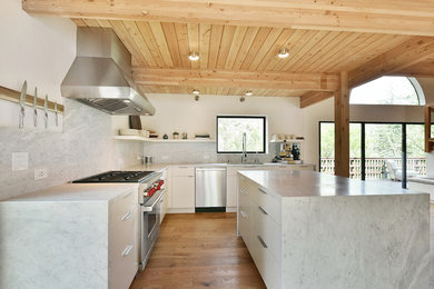 Inspiration for a large modern l-shaped light wood floor open concept kitchen remodel in Los Angeles with an undermount sink, flat-panel cabinets, white cabinets, marble countertops, marble backsplash and an island