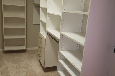 Ejemplo de armario vestidor de mujer minimalista con puertas de armario blancas y suelo de madera clara
