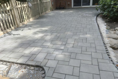 Example of a mid-sized trendy backyard stone patio design in DC Metro with no cover