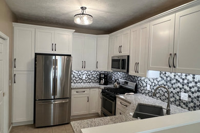 Example of a mid-sized classic u-shaped eat-in kitchen design in Cleveland with shaker cabinets, white cabinets, quartz countertops and mosaic tile backsplash