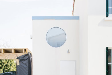 Réalisation d'une petite façade de maison blanche design à un étage avec un revêtement mixte et un toit en métal.