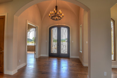 Entryway - mediterranean medium tone wood floor entryway idea in Austin with beige walls and a black front door