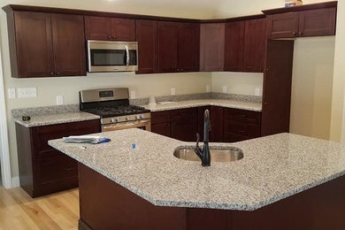 Light wood floor kitchen photo in Manchester with recessed-panel cabinets, brown cabinets and granite countertops