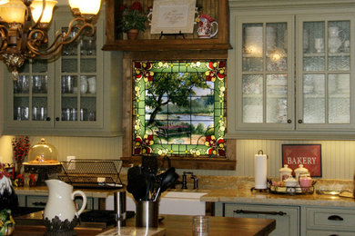 Mid-sized elegant l-shaped eat-in kitchen photo in Dallas with an island, glass-front cabinets, green cabinets, granite countertops and beige backsplash
