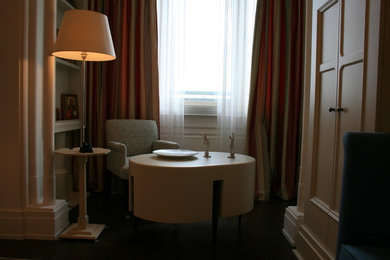 На фото: изолированная гостиная комната среднего размера в стиле фьюжн с с книжными шкафами и полками, белыми стенами, паркетным полом среднего тона, телевизором на стене и коричневым полом