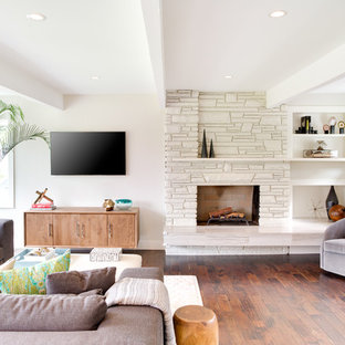 Bild på ett mellanstort funkis allrum med öppen planlösning, med vita väggar, en öppen hörnspis, en spiselkrans i sten, en väggmonterad TV och laminatgolv
