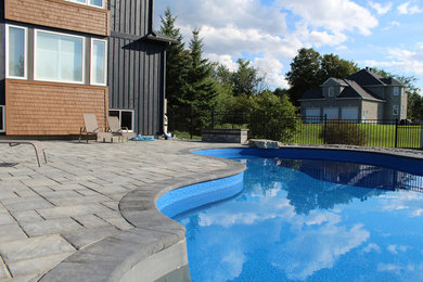 Photo of a large modern backyard pool in Ottawa with brick pavers.