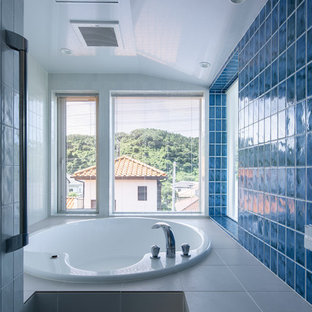 Immagine di una stanza da bagno padronale minimalista di medie dimensioni con vasca idromassaggio, zona vasca/doccia separata, piastrelle blu, piastrelle in gres porcellanato, pareti blu, pavimento in gres porcellanato e pavimento bianco