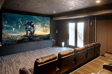 Photo of a modern home theatre in San Francisco with black walls, carpet and a projector screen.