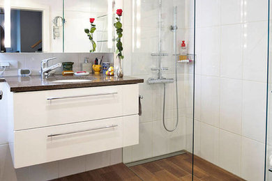 Mittelgroßes Modernes Duschbad mit bodengleicher Dusche, weißer Wandfarbe, braunem Boden, flächenbündigen Schrankfronten, weißen Schränken, Wandtoilette mit Spülkasten, Porzellanfliesen, hellem Holzboden, Waschtischkonsole, Granit-Waschbecken/Waschtisch, offener Dusche und weißer Waschtischplatte in Frankfurt am Main