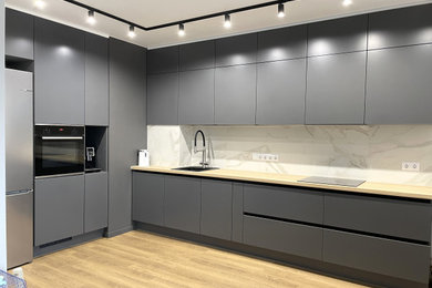 Large contemporary l-shaped open plan kitchen in Saint Petersburg with a submerged sink, flat-panel cabinets, grey cabinets, laminate countertops, white splashback, ceramic splashback, black appliances, no island and beige worktops.