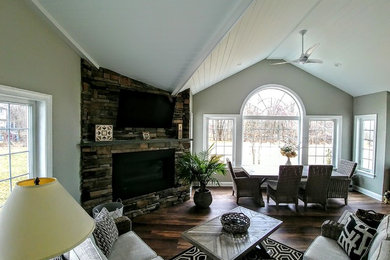 Example of a large classic open concept dark wood floor and brown floor living room design in Philadelphia with a standard fireplace, a stone fireplace, a wall-mounted tv and gray walls
