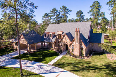 Inspiration for a mid-sized timeless beige two-story stone gable roof remodel in Houston with a shingle roof