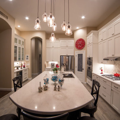 Huge elegant u-shaped porcelain tile and brown floor open concept kitchen photo in Phoenix with an undermount sink, shaker cabinets, white cabinets, quartzite countertops, multicolored backsplash, mosaic tile backsplash, stainless steel appliances, an island and white countertops