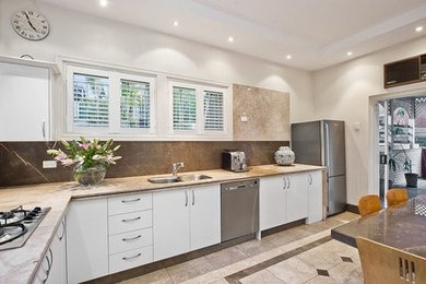 Cette image montre une cuisine minimaliste en L de taille moyenne avec un plan de travail en calcaire, une crédence en pierre calcaire et un sol en calcaire.