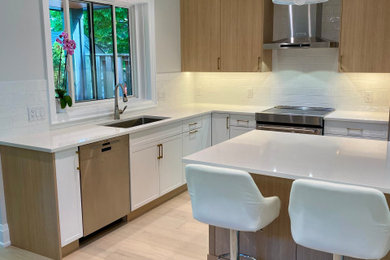Mid-sized trendy light wood floor open concept kitchen photo in Toronto with an undermount sink, flat-panel cabinets, quartz countertops, white backsplash, porcelain backsplash, stainless steel appliances, an island and white countertops