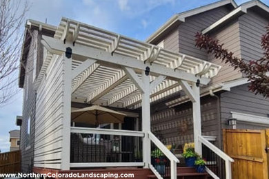 Inspiration for a mid-sized backyard ground level privacy deck remodel in Denver with a pergola