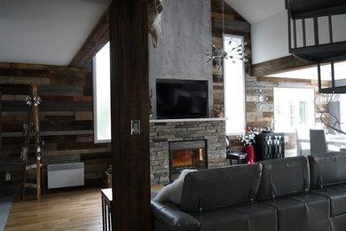 Foto de sala de estar tipo loft urbana de tamaño medio con paredes grises, suelo de madera clara, todas las chimeneas, marco de chimenea de piedra y pared multimedia