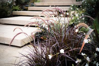 Medium sized modern sloped xeriscape partial sun garden for summer in Other with a fireplace and natural stone paving.