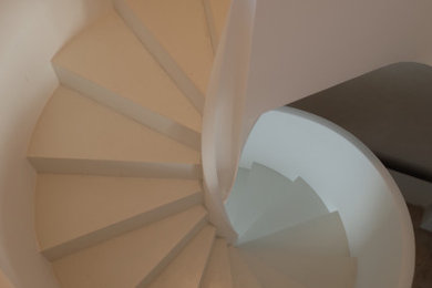 Réalisation d'un escalier hélicoïdal design avec un garde-corps en matériaux mixtes et éclairage.