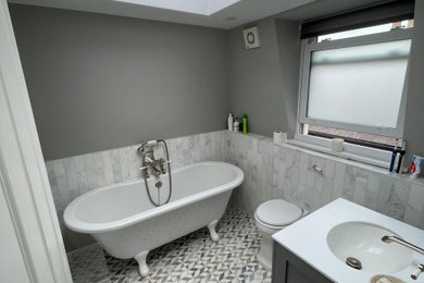 Diseño de cuarto de baño infantil, único y flotante clásico de tamaño medio con armarios estilo shaker, puertas de armario grises, bañera con patas, sanitario de una pieza y encimera de cuarcita
