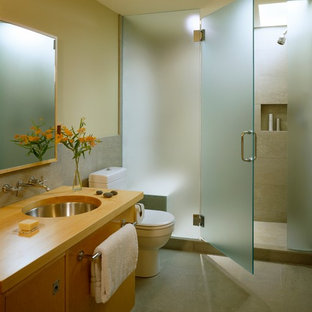 Ispirazione per una piccola stanza da bagno con doccia moderna con lavabo sottopiano, ante lisce, ante in legno chiaro, top in legno, doccia alcova, WC a due pezzi, piastrelle grigie, piastrelle in pietra, pareti verdi e pavimento in pietra calcarea