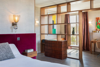 Cette image montre une grande chambre parentale design avec un mur beige, parquet foncé et un sol marron.