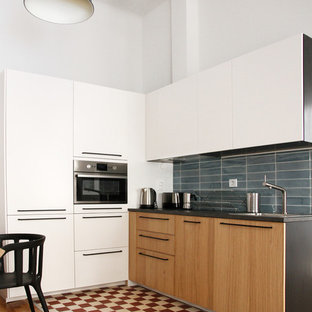 Неиссякаемый источник вдохновения для домашнего уюта: маленькая угловая кухня-гостиная в современном стиле с одинарной раковиной, плоскими фасадами, фасадами цвета дерева среднего тона, синим фартуком, фартуком из керамической плитки, техникой под мебельный фасад, полом из цементной плитки и красным полом