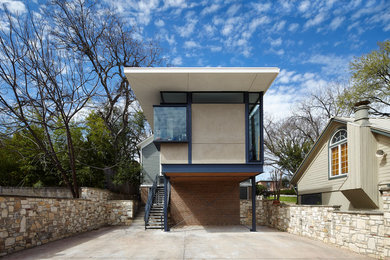 This is an example of a mid-sized modern two-storey beige house exterior in Austin with mixed siding and a flat roof.