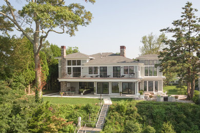 Trendy gray three-story house exterior photo in New York with a shingle roof