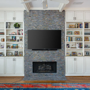 Mediterranes Wohnzimmer mit rosa Wandfarbe, braunem Holzboden, Kamin, Kaminsims aus Stein, Wand-TV und braunem Boden in Dallas