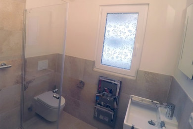 Kleines Modernes Duschbad mit Eckdusche, Wandtoilette, Porzellanfliesen, weißer Wandfarbe, Porzellan-Bodenfliesen, Einbauwaschbecken und Falttür-Duschabtrennung in München