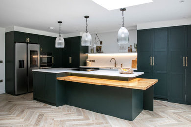 Contemporary l-shaped open plan kitchen in Other with shaker cabinets, green cabinets, quartz worktops, white splashback, engineered quartz splashback, integrated appliances, an island and white worktops.