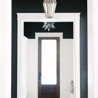 Cette image montre une entrée bohème de taille moyenne avec un vestiaire, un mur noir, un sol en carrelage de céramique, une porte simple et une porte en bois foncé.