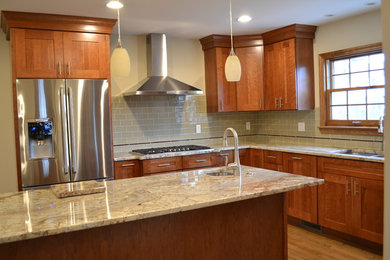Inspiration for a mid-sized timeless u-shaped medium tone wood floor eat-in kitchen remodel in Columbus with a drop-in sink, recessed-panel cabinets, medium tone wood cabinets, granite countertops, green backsplash, subway tile backsplash, stainless steel appliances and an island