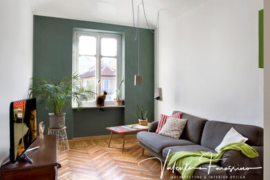 Idee per un piccolo soggiorno boho chic chiuso con libreria, pareti verdi e pavimento in legno verniciato