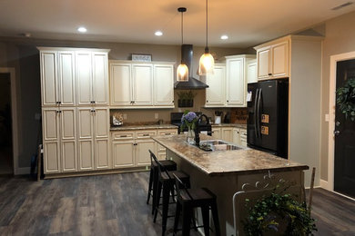 This is an example of a large contemporary l-shaped eat-in kitchen in Chicago with a drop-in sink, raised-panel cabinets, beige cabinets, laminate benchtops, black appliances, with island and brown benchtop.