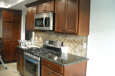 Inspiration for a mid-sized transitional single-wall ceramic tile and beige floor enclosed kitchen remodel in Los Angeles with recessed-panel cabinets, dark wood cabinets, granite countertops, beige backsplash, stone tile backsplash, stainless steel appliances and no island