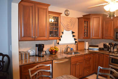 Small elegant l-shaped ceramic tile and beige floor eat-in kitchen photo in New York with an undermount sink, raised-panel cabinets, medium tone wood cabinets, granite countertops, beige backsplash, stainless steel appliances, ceramic backsplash and no island