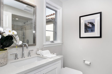 Alcove shower - large traditional 3/4 alcove shower idea in Los Angeles with shaker cabinets, white cabinets, a one-piece toilet, white walls, an undermount sink, quartz countertops, a hinged shower door and white countertops