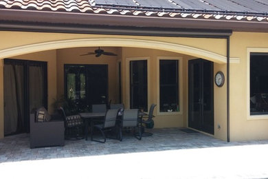 Mid-sized elegant backyard stone patio photo in Orange County with a roof extension